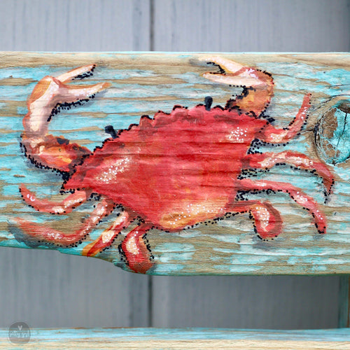 a wooden bench with a painted crab design on it.