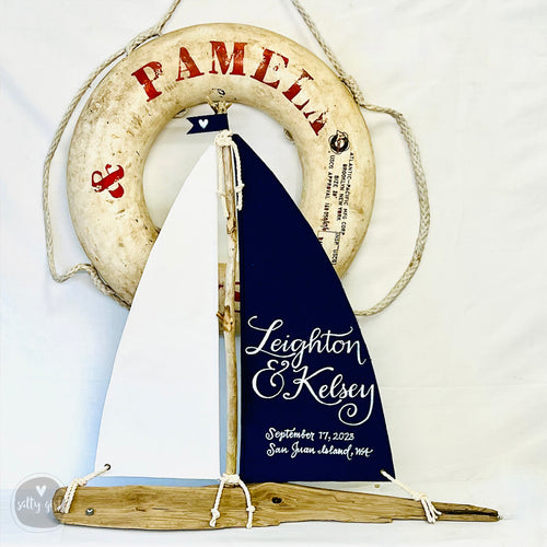 a nautical-themed wedding invitation with a sailboat design, a life preserver, and a wooden boat.