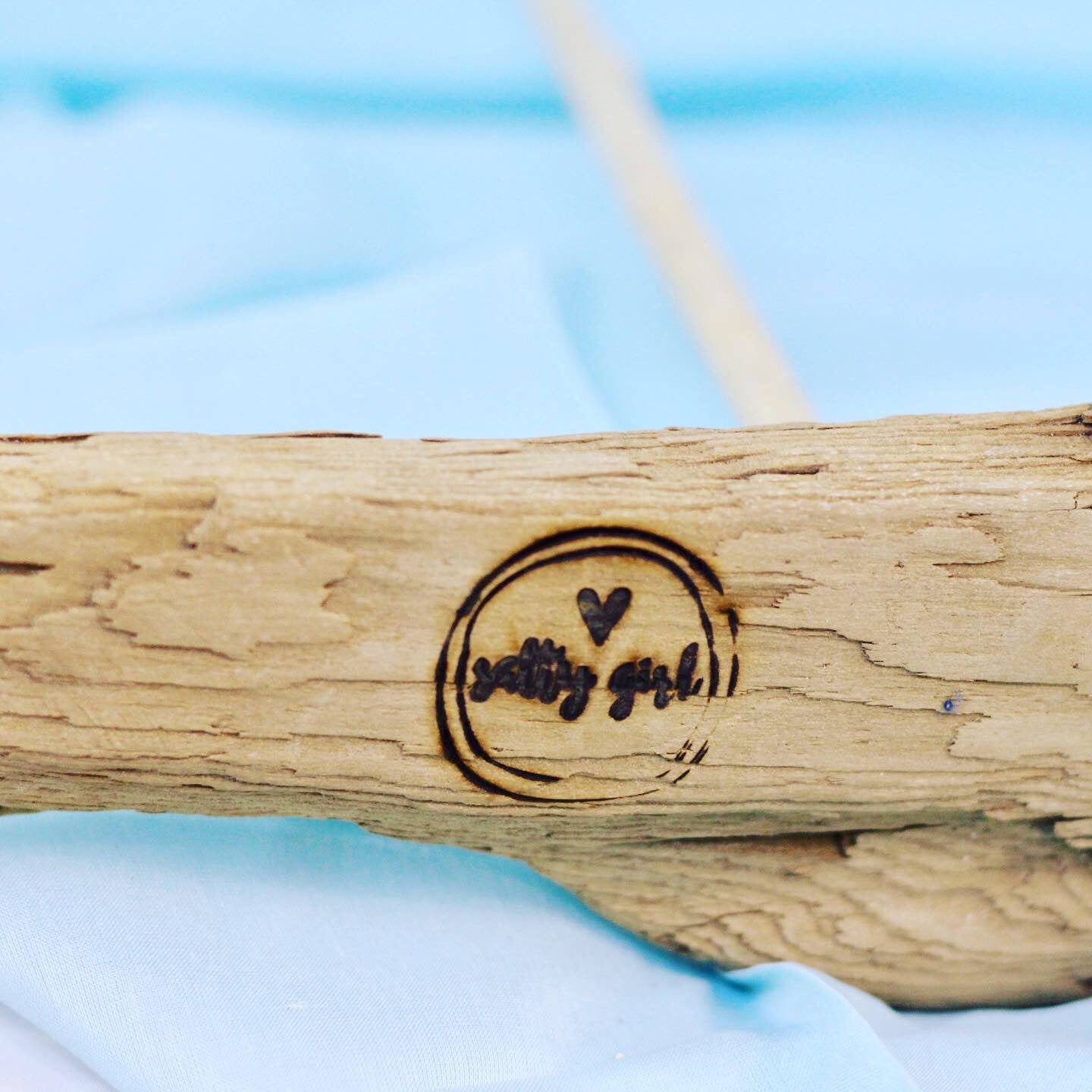 business logo branded on bottom of driftwood sailboat