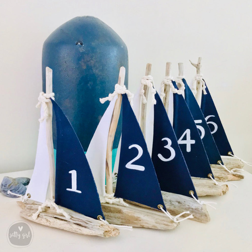 a collection of small blue and white sailboat-shaped objects, each with a number on it, arranged on a white surface.