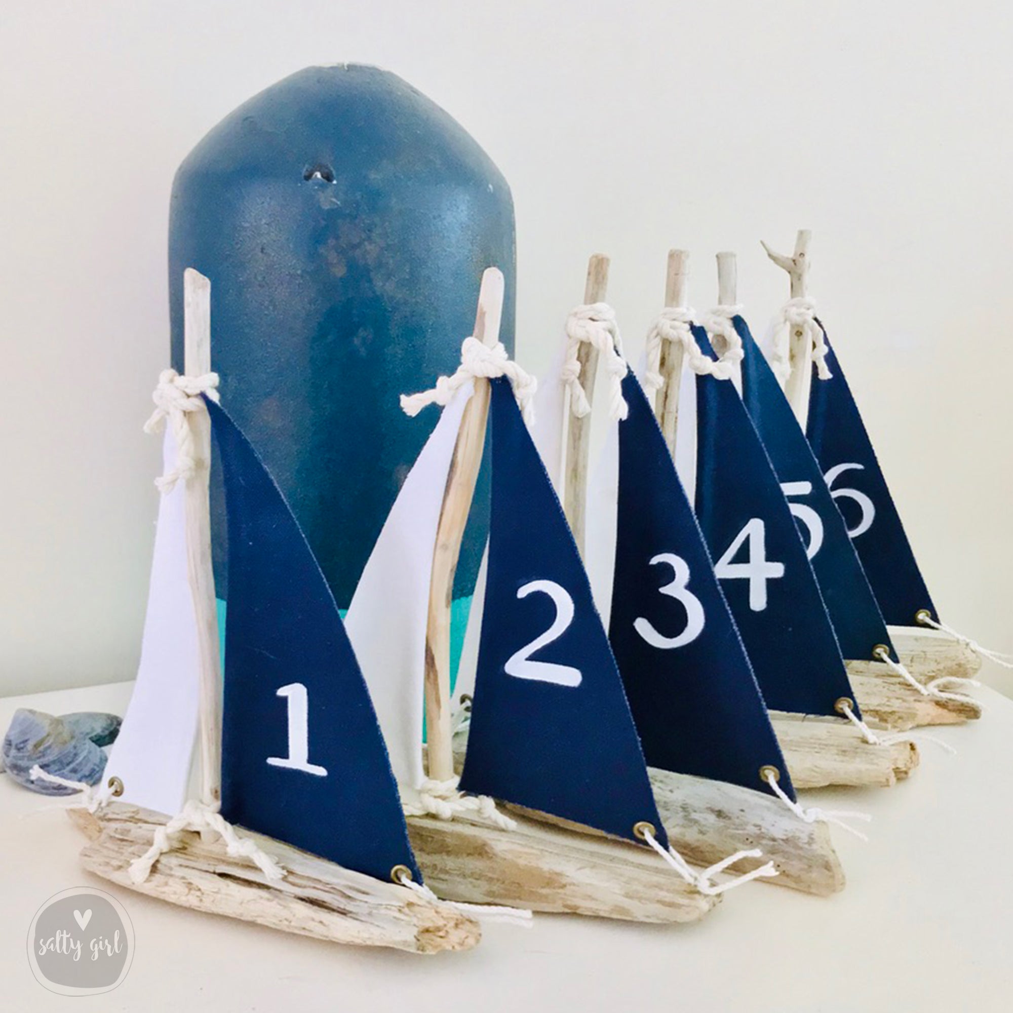 a collection of small blue and white sailboat-shaped objects, each with a number on it, arranged on a white surface.