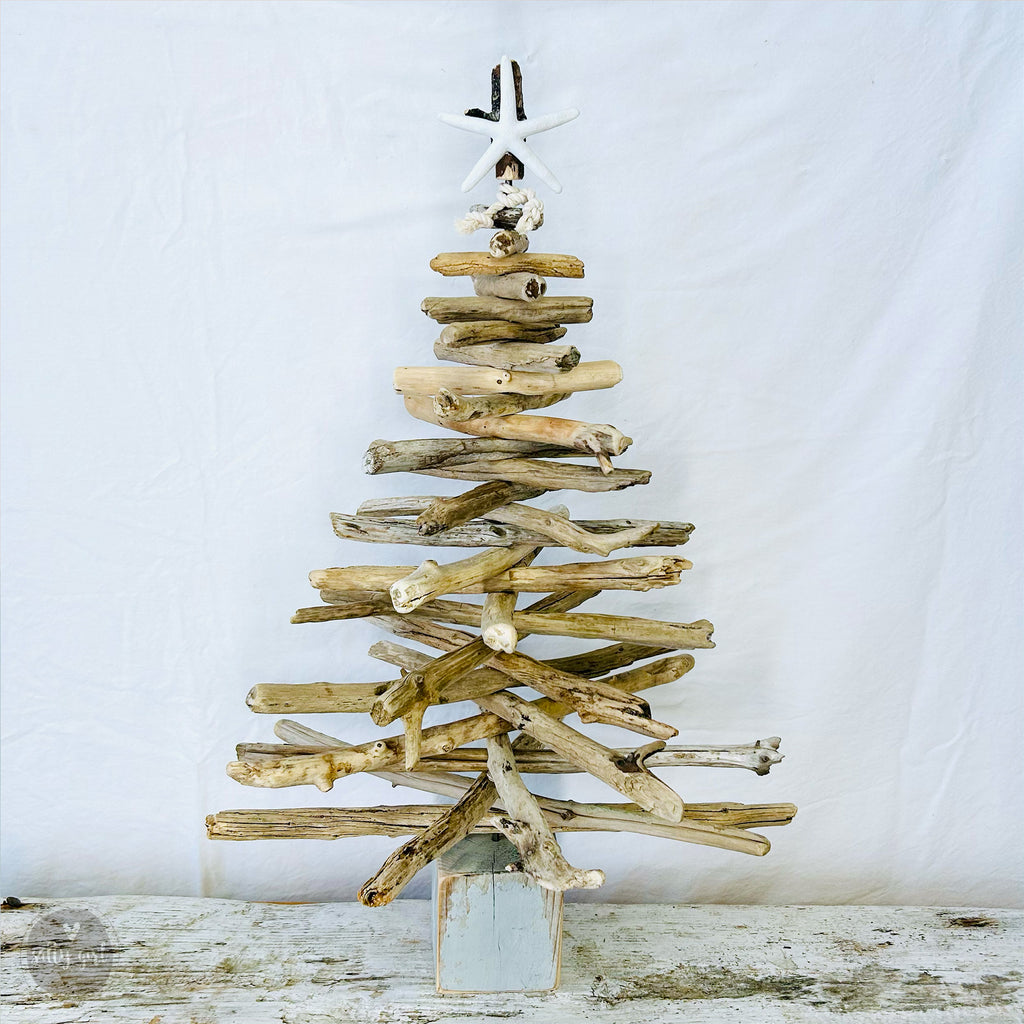 a wooden christmas tree made out of driftwood with starfish tree topper