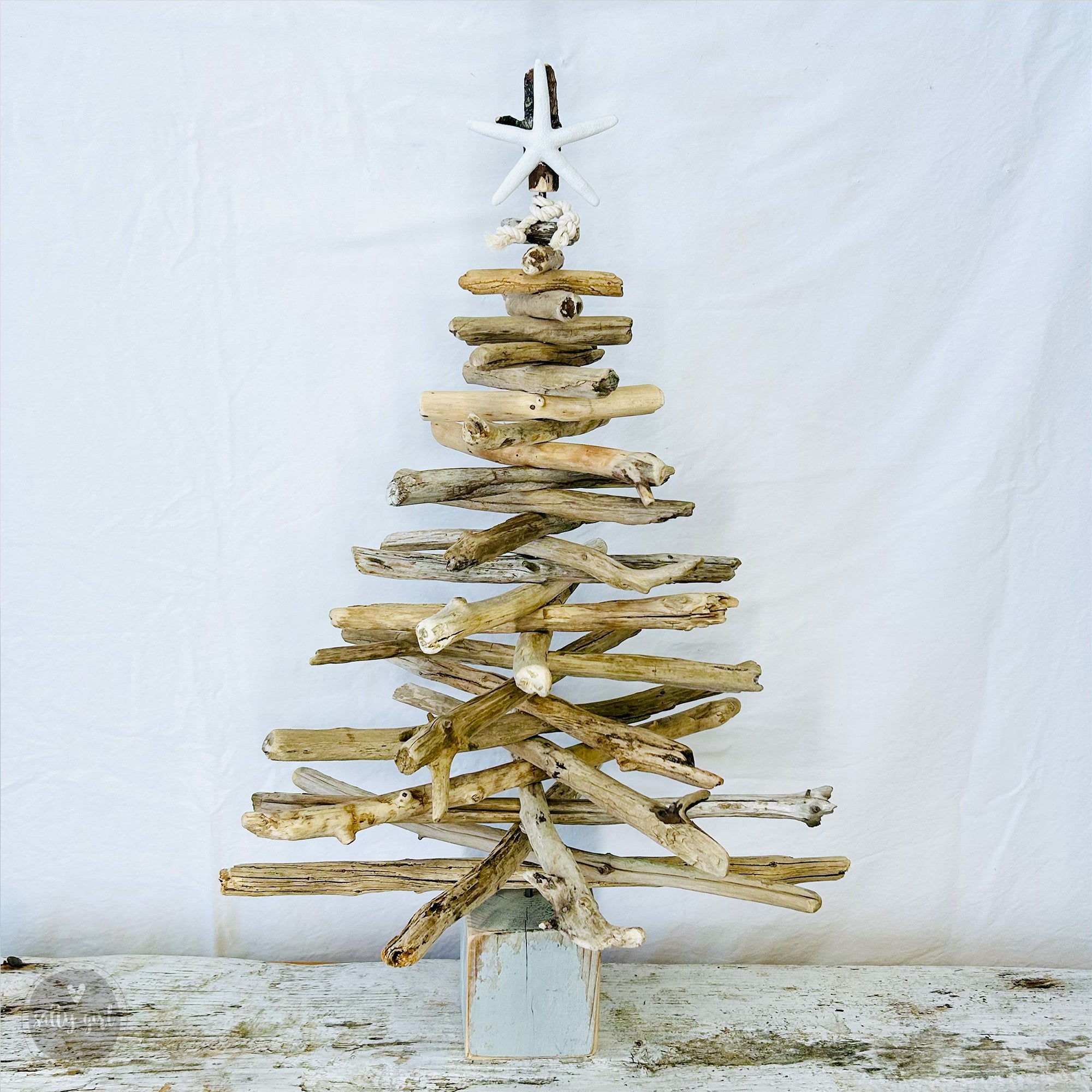 a wooden christmas tree made out of driftwood with starfish tree topper